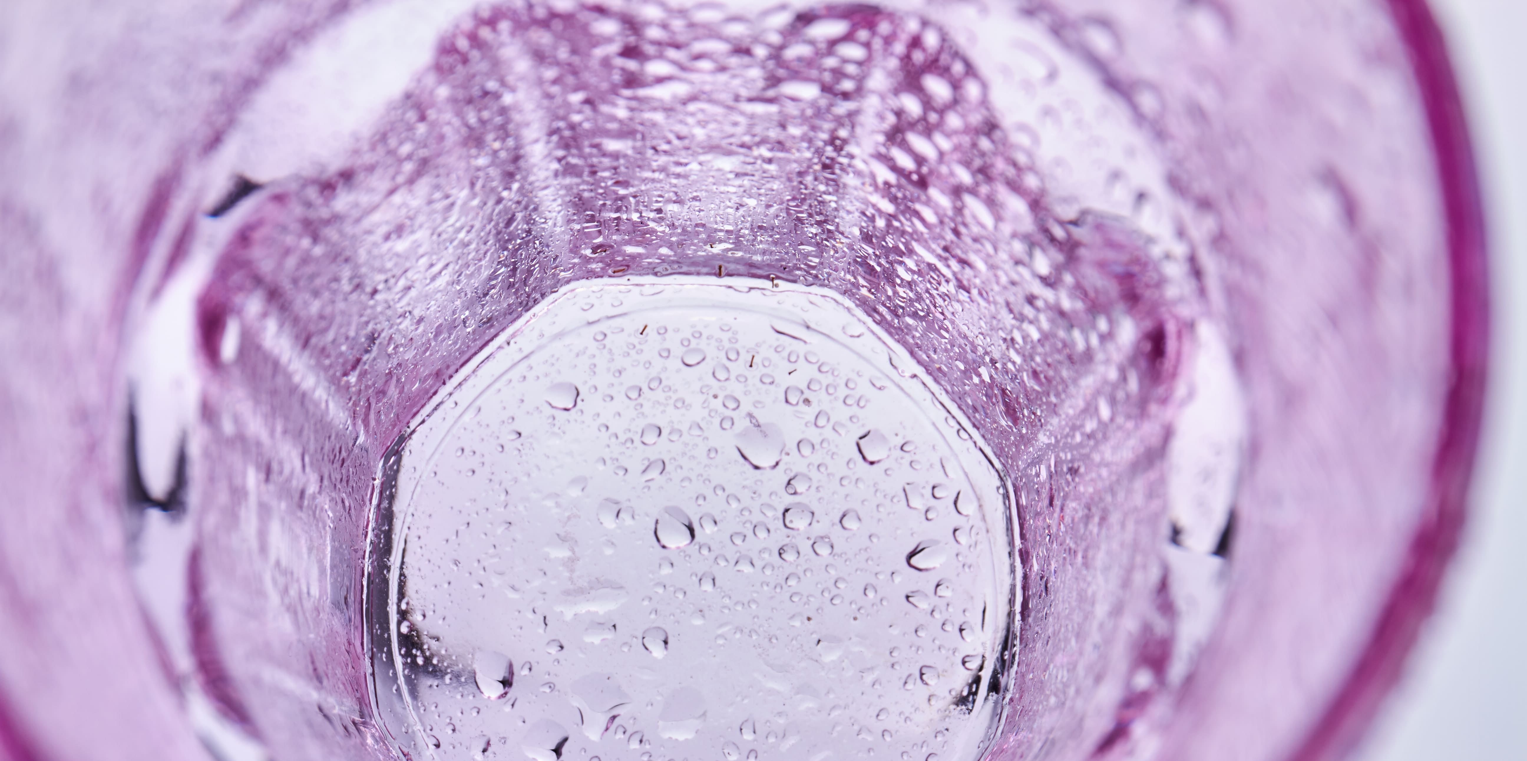 Close-up of a pink glass with water droplets on a blurred background